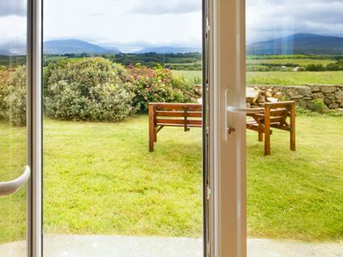 A garden with wooden benches and bushes seen through glass doors at Coed Bolyn Lodge in Bethel