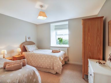 A bedroom with two single beds wooden wardrobe white chest of drawers and a window with flowers at Coed Bolyn Lodge in Bethel