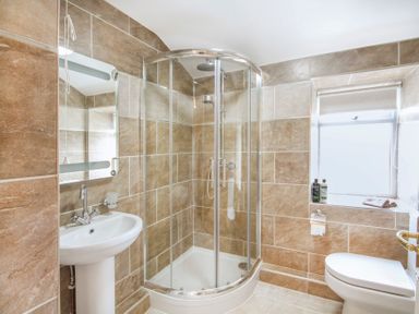 A bathroom with a glass shower enclosure a white sink a toilet and a window at Coed Bolyn Lodge in Bethel
