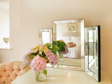 A mirror reflecting a bed with folded towels and a painting with flowers in a bedroom at Coed Bolyn Lodge in Bethel