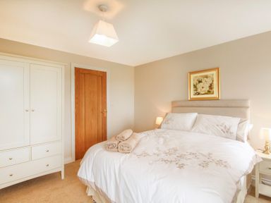 A bedroom with a bed towels on it a white wardrobe a wooden door and a framed picture on the wall at Coed Bolyn Lodge in Bethel
