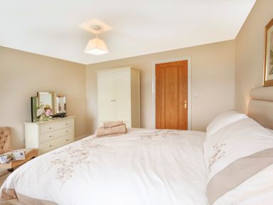 A bedroom with a bed towels wardrobe dresser with mirror and flowers at Coed Bolyn Lodge in Bethel