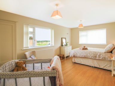 A bedroom with a bed a crib a dresser and two windows at Coed Bolyn Lodge in Bethel