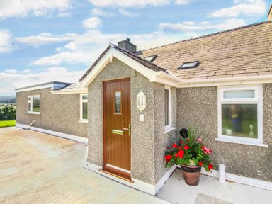 A house exterior with a wooden door and flower pot on a concrete driveway at Coed Bolyn Lodge in Bethel