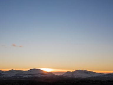 A sunset over snow covered mountains with a clear sky at Coed Bolyn Lodge in Bethel