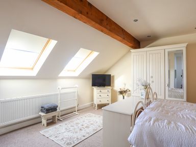 A bedroom with a bed dresser wardrobe and skylight windows at Cosy Barn in Llangaffo