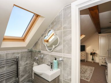 A bathroom with a small sink mirror and skylight window at Cosy Barn in Llangaffo