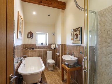 A bathroom with a bathtub toilet sink and shower at Cosy Barn in Llangaffo