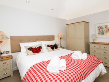 A bedroom with a double bed with butterfly pillows and red checkered blanket at Cuckooland in Borth-Y-Gest
