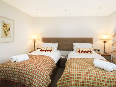 A bedroom with two single beds side by side each with a patterned blanket and a rolled towel on top Cuckooland Borth-Y-Gest