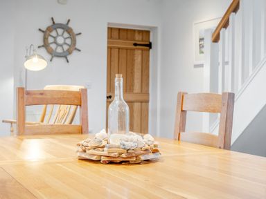 A dining room with a wooden table and chairs at Curragho in Trearddur Bay