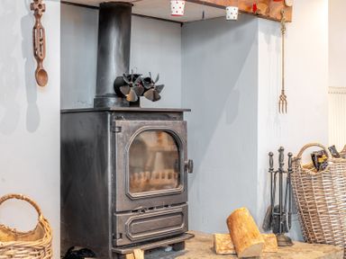 A stove with firewood beside it at Curragho in Trearddur Bay