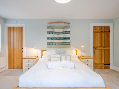 A bedroom with a bed, side tables, and lamps at Curragho in Trearddur Bay