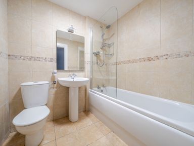 A bathroom with shower, bathtub, sink, and toilet at Curragho in Trearddur Bay