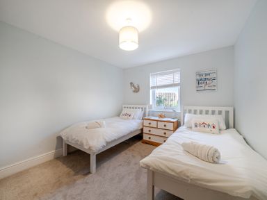A bedroom with twin beds and a dresser at Curragho in Trearddur Bay