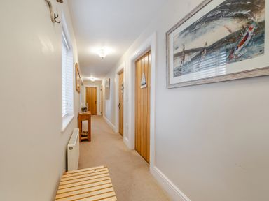 A hallway with doors and a table at Curragho in Trearddur Bay