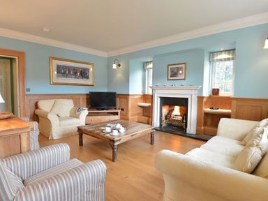 A living room with a fireplace a television wooden coffee table and various sofas at Dinas Noddfa in Nant Gwynant
