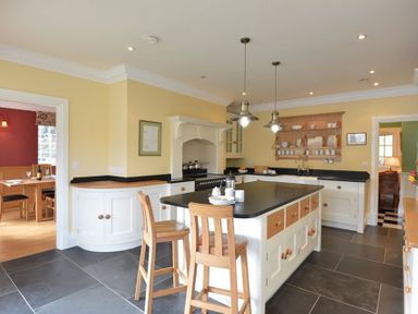 A kitchen with island and wooden stools and hanging lights at Dinas Noddfa in Nant Gwynant