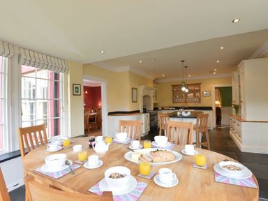 A kitchen with wooden dining tables and chairs set with breakfast items at Dinas Noddfa in Nant Gwynant