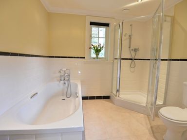 A bathroom with a bathtub shower enclosure toilet and a window with tulips at Dinas Noddfa in Nant Gwynant