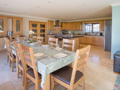 A dining area with a long table set with plates and glasses next to a kitchen with wooden cabinets and a central island at Dol Fraint in Star
