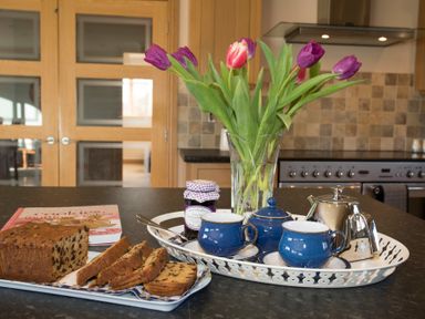 A kitchen counter with a tray holding a teapot sugar bowl and two cups a vase with tulips and sliced fruit bread at Dol Fraint in Star