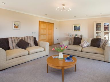 A living room with two beige sofas and a wooden coffee table with flowers at Dol Fraint in Star