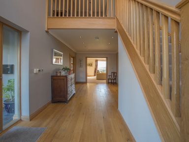A hallway with wooden flooring a wooden staircase a wooden chest of drawers and a wooden chair at Dol Fraint in Star