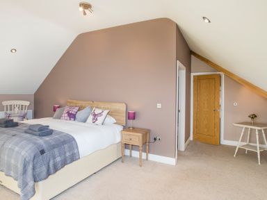 A bedroom with a double bed with cushions bedside tables with lamps a wooden door and a small table with flowers at Dol Fraint in Star
