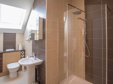 A bathroom with a shower enclosure a toilet a sink and a cabinet under a skylight at Dol Fraint in Star