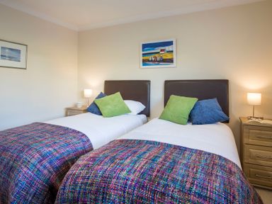 A bedroom with two single beds each with a blue and green pillow and multicolored blankets at Dol Fraint in Star