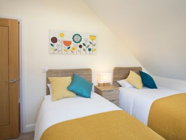 A bedroom with two single beds a bedside table and a floral painting on the wall at Dol Fraint in Star