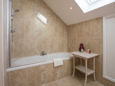 A bathroom with a bathtub shower combination and a small table with toiletries at Dol Fraint in Star