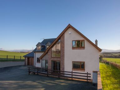 A detached house with brick and white walls surrounded by green fields at Dol Fraint in Star