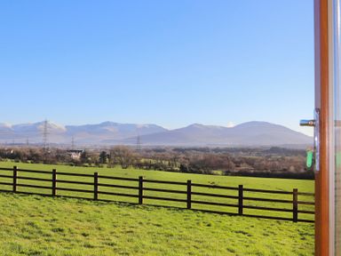 A green field with a wooden fence and mountains in the background seen through an open door at Dol Fraint in Star