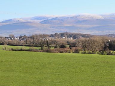 A green field with trees and houses with hills in the background at Dol Fraint in Star
