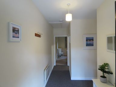 A hallway with coat hooks and framed pictures at Bryn Eira Tack Room in Llanfair PG