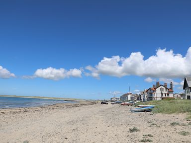A sandy beach with boats and houses along the shore at Flip Flops in Rhosneigr