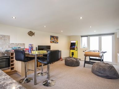 A game room with a foosball table bean bags an arcade machine board games and high chairs at Flip Flops in Rhosneigr