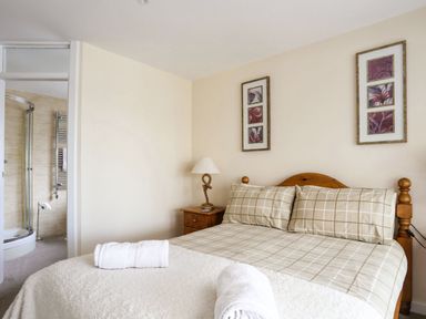 A bedroom with a bed and folded towels and a bathroom visible through an open door at Flip Flops in Rhosneigr
