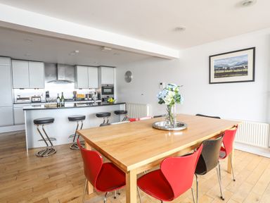 A kitchen with a dining table and red and black chairs four The Quay in Red Wharf Bay