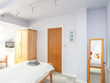 A bedroom with a wooden wardrobe bed with white bedding and a wooden-framed mirror at Four The Quay in Red Wharf Bay