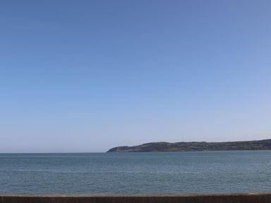 A view of the sea with a distant headland under a clear sky at Four The Quay in Red Wharf Bay