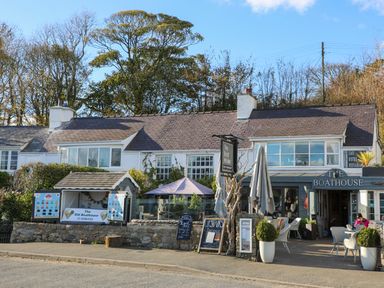 The exterior of a cafe and restaurant with outdoor seating and signs at Four The Quay in Red Wharf Bay