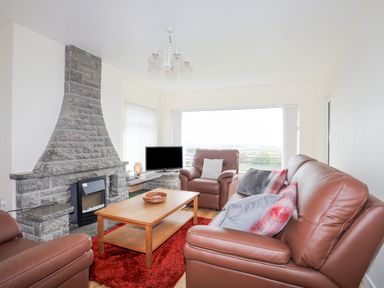 A living room with brown leather sofas a stone fireplace a wooden coffee table and a television at Frondeg in Rhiwlas