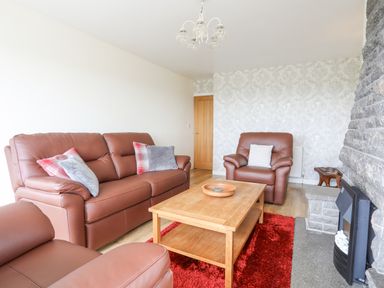 A living room with brown leather sofas wooden coffee table and stone fireplace at Frondeg in Rhiwlas