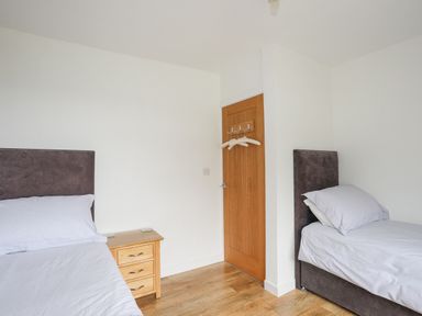 A bedroom with two single beds and a wooden door with hangers at Frondeg in Rhiwlas