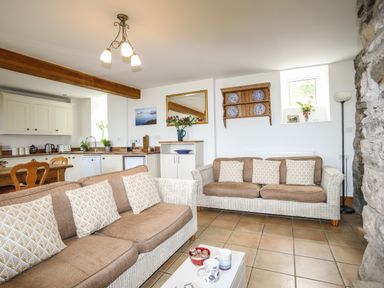A living room with two sofas and a kitchen area in the background at Fron Fawr in Nefyn