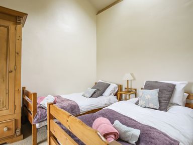 A bedroom with two single wooden beds a wooden wardrobe and a bedside table with a lamp at Fron Fawr in Nefyn
