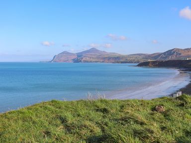 A coastal landscape with hills in the background a sandy beach and grassy foreground at Fron Fawr in Nefyn